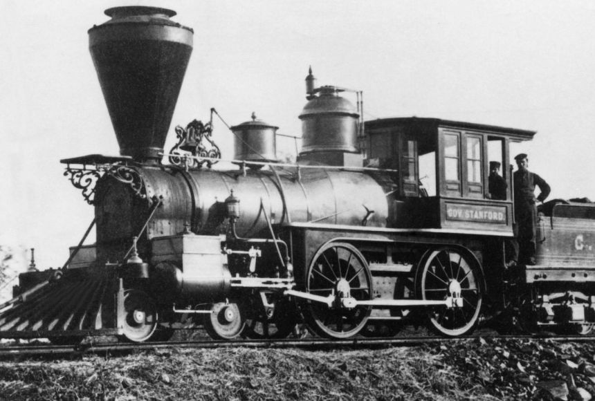 Early steam train with conductors on board.